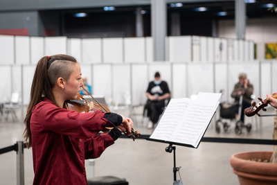 910146 Afbeelding van een violist in de XL- vaccinatielocatie in de Jaarbeurs te Utrecht, waar live klassieke muziek ...